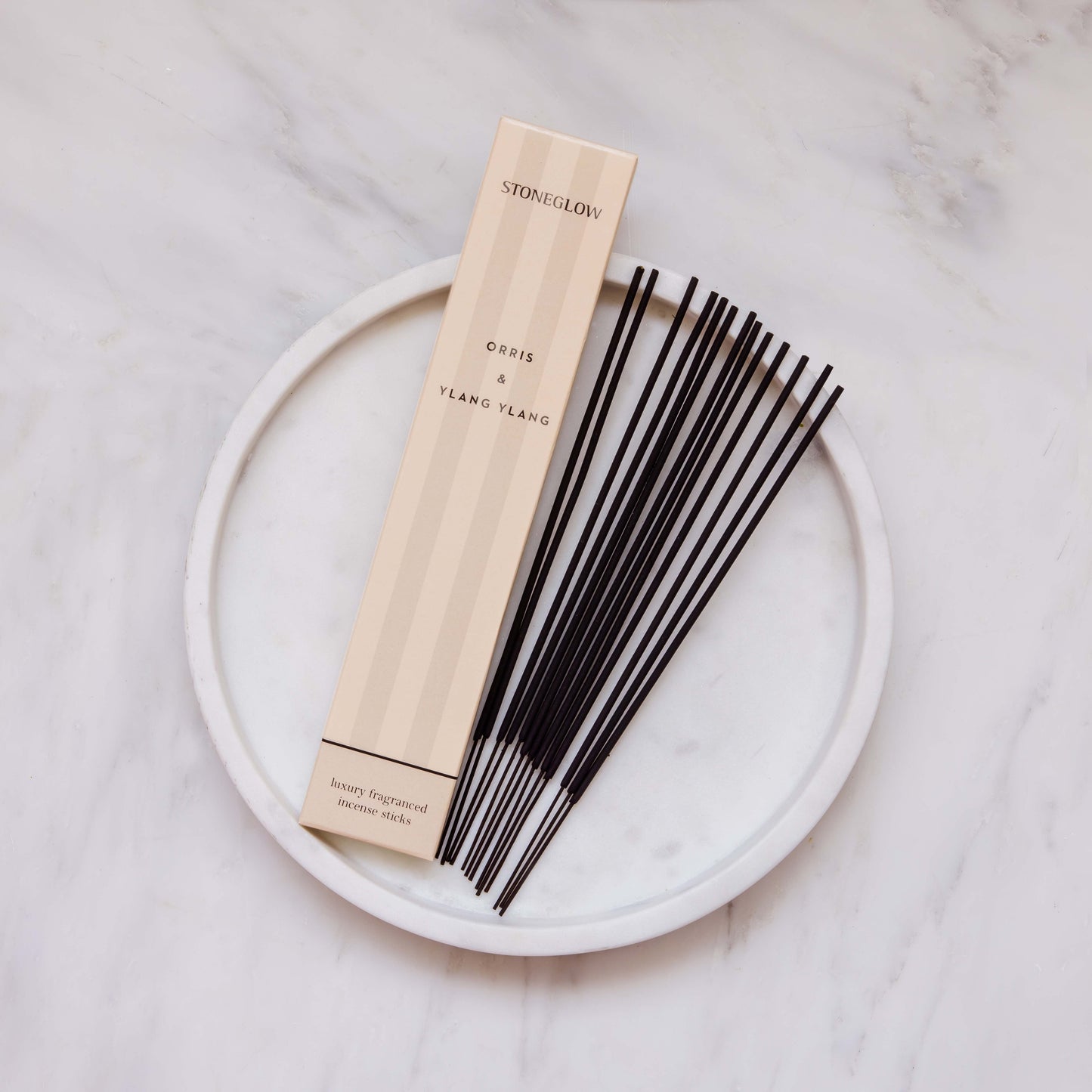 Incense sticks with packaging on a white plate against a light background