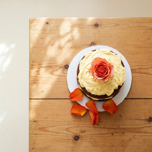Top-down view of Carrot Cake in Bloom, a fresh coral rose centred on the cream cheese frosting of a carrot cake