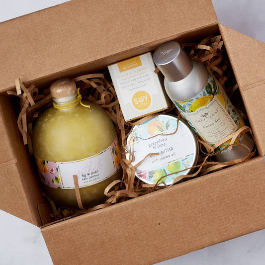 Close-up of Citrus Spa Gift Box with bath crystals, body butter, soy candle, and citrus spray nestled in a gift box with shredded filler.