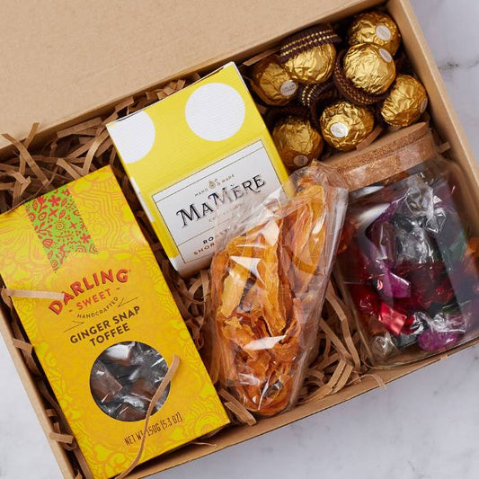 Close-up on the Ginger Snap & Gold Box gourmet hamper by Flower Guy featuring artisan ginger snap toffee, Ferrero Rocher, dried fruit, and luxury chocolates.