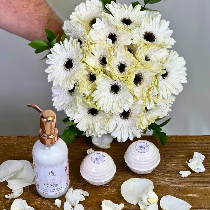 Dinaledi Pomegranate and Vanilla Hand & Body Lotion Next to Heavenly Petals and two bath bombs - Flower Guy