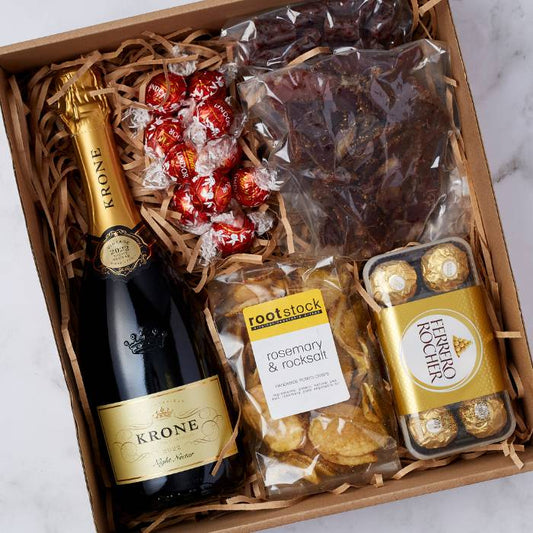 Close-up view of the Krone & Crisp Exquisite Snack Hamper displaying a premium bottle of Krone MCC, gourmet snacks, and chocolates arranged elegantly in a gift box.
Close-up view of the Krone & Crisp Exquisite Snack Hamper displaying a premium bottle of Krone MCC, gourmet snacks, and chocolates arranged elegantly in a gift box.