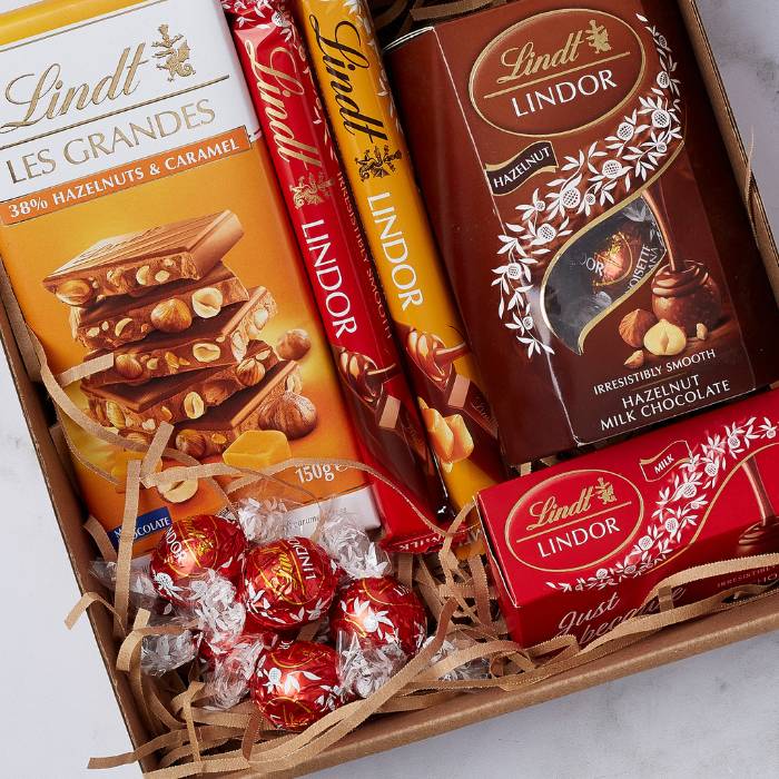 Close-up on the Lindt Lovers Gift Box by Flower Guy featuring Lindt Les Grandes bar, Lindor truffles, chocolate sticks, and hazelnut milk chocolate.
