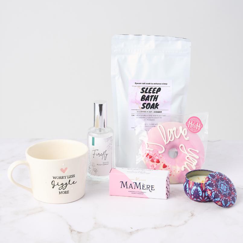 Lovely Lady Gift Set from Flower Guy, featuring a 'Worry Less, Giggle More' mug, Sleep Bath Soak, Firefly Room Spray, 'Love You' bath bomb, MaMère Almond Nougat, and a decorative tin candle.