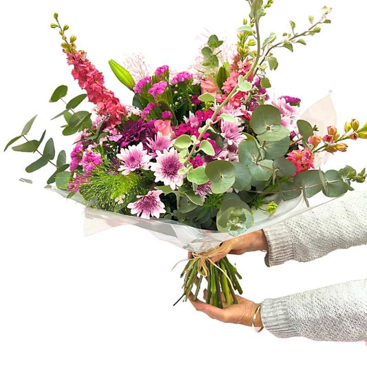 One of a Kind bouquet close-up in wrapping—radiant mixed flowers with greenery, ready to gift | Flower Guy