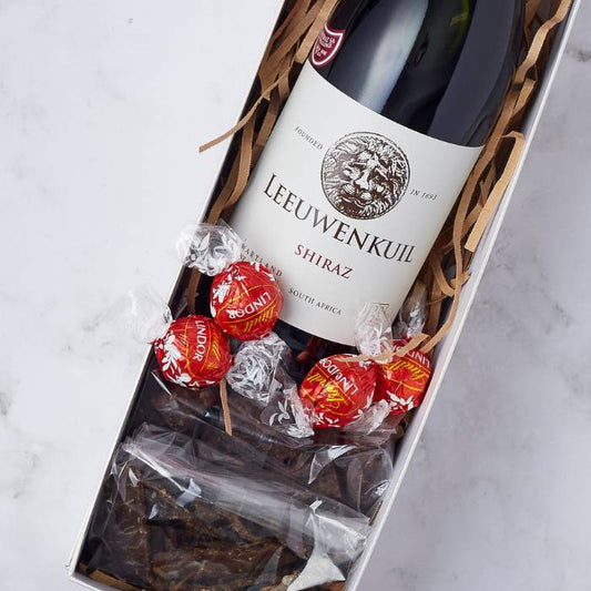 Close-up on Shiraz & Chocolate Delight gift box featuring a bottle of Leeuwenkuil Shiraz, Lindt chocolate truffles, and biltong by Flower Guy.