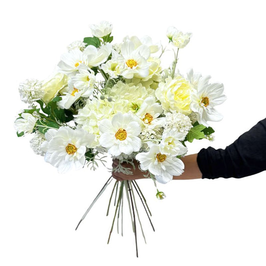 Bouquet of white and yellow flowers held by a person against a white background