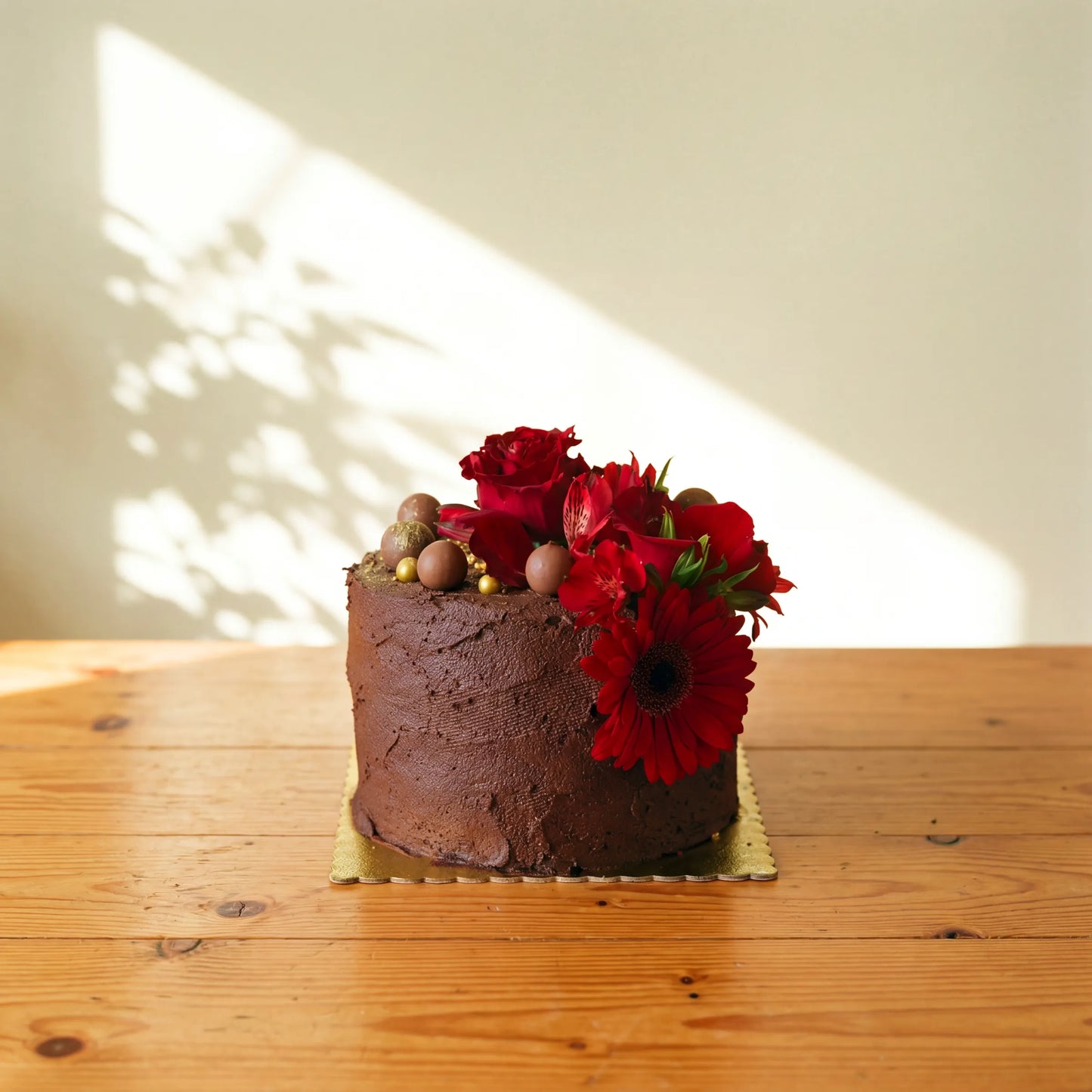 Single tier chocolate cake with rich ganache frosting, topped with fresh red roses, red gerbera daisies, red alstroemerias and chocolate truffles, hand-finished by Flower Guy Cape Town
