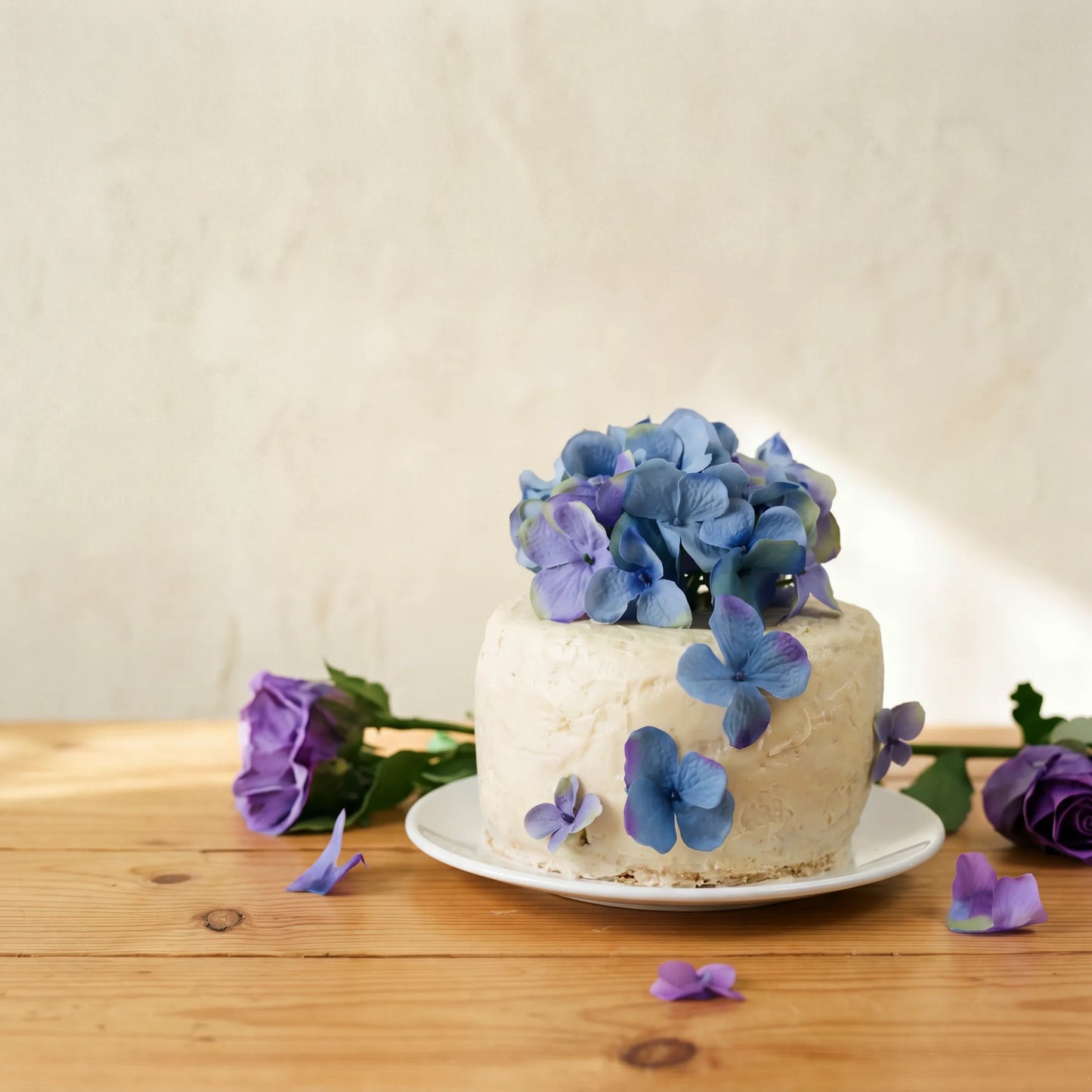 Side angle of Blue Blossom Harmony Madeira Cake showing rustic vanilla icing and blue hydrangea blooms