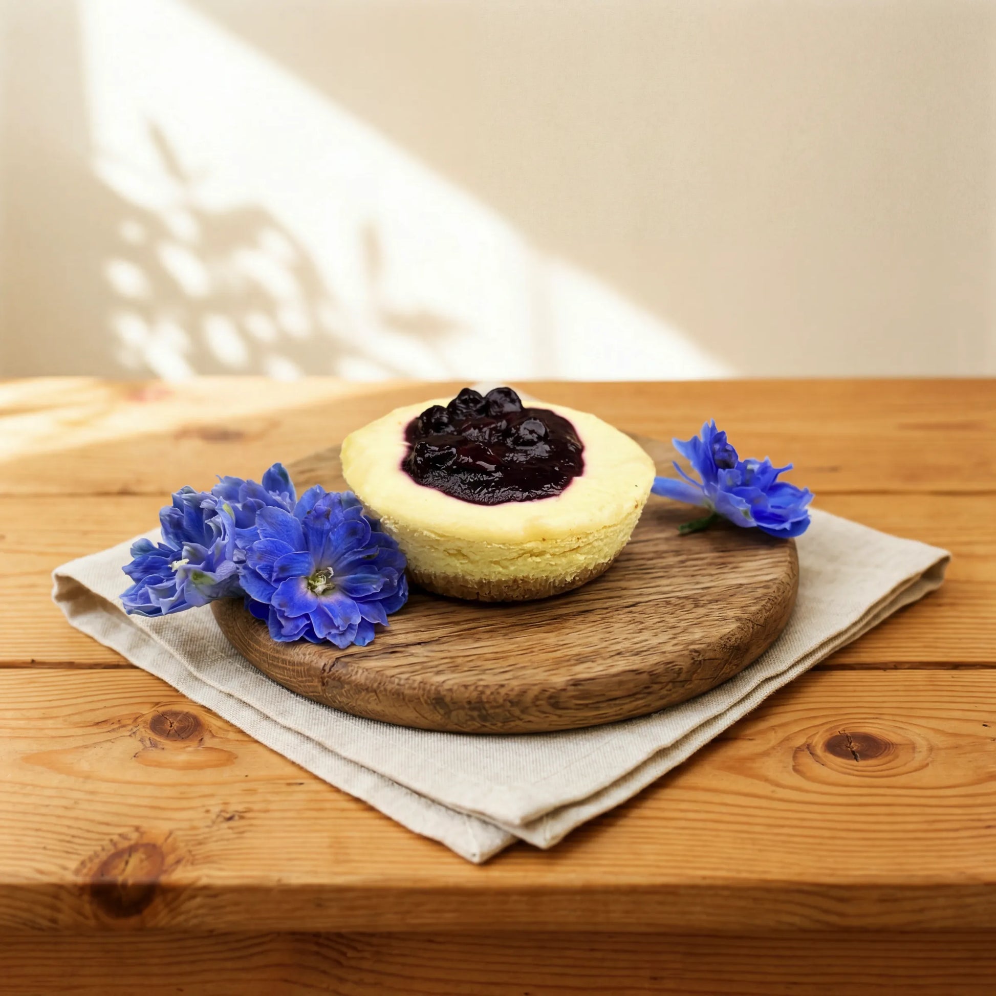 Blueberry Cheesecake single-portion treat styled with fresh blue delphinium by Flower Guy Cape Town