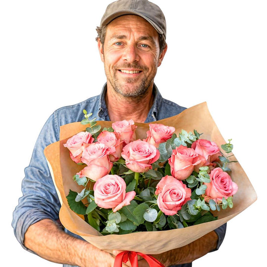 Blush Harmony rose flower bouquet—man holding 12 soft pink roses with greenery, wrapped in kraft paper | Flower Guy