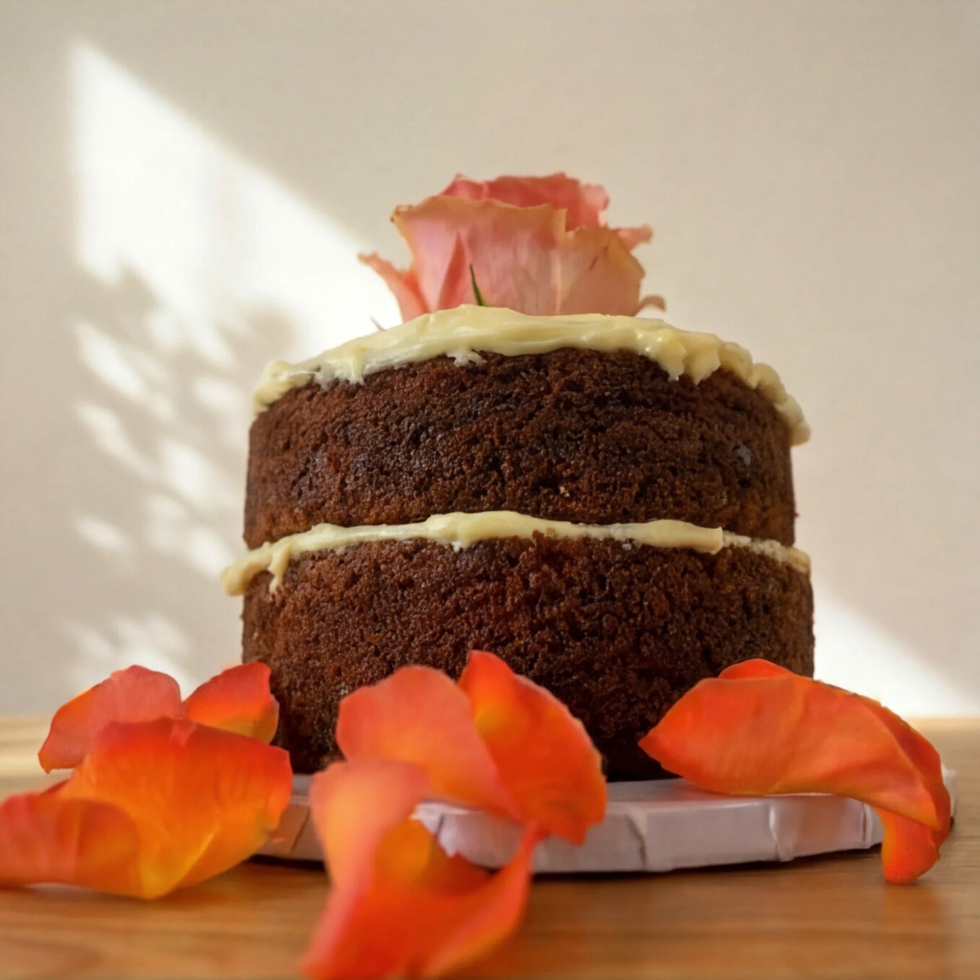 Carrot Cake in Bloom close up, two naked carrot sponge layers with cream cheese frosting and a rose on top