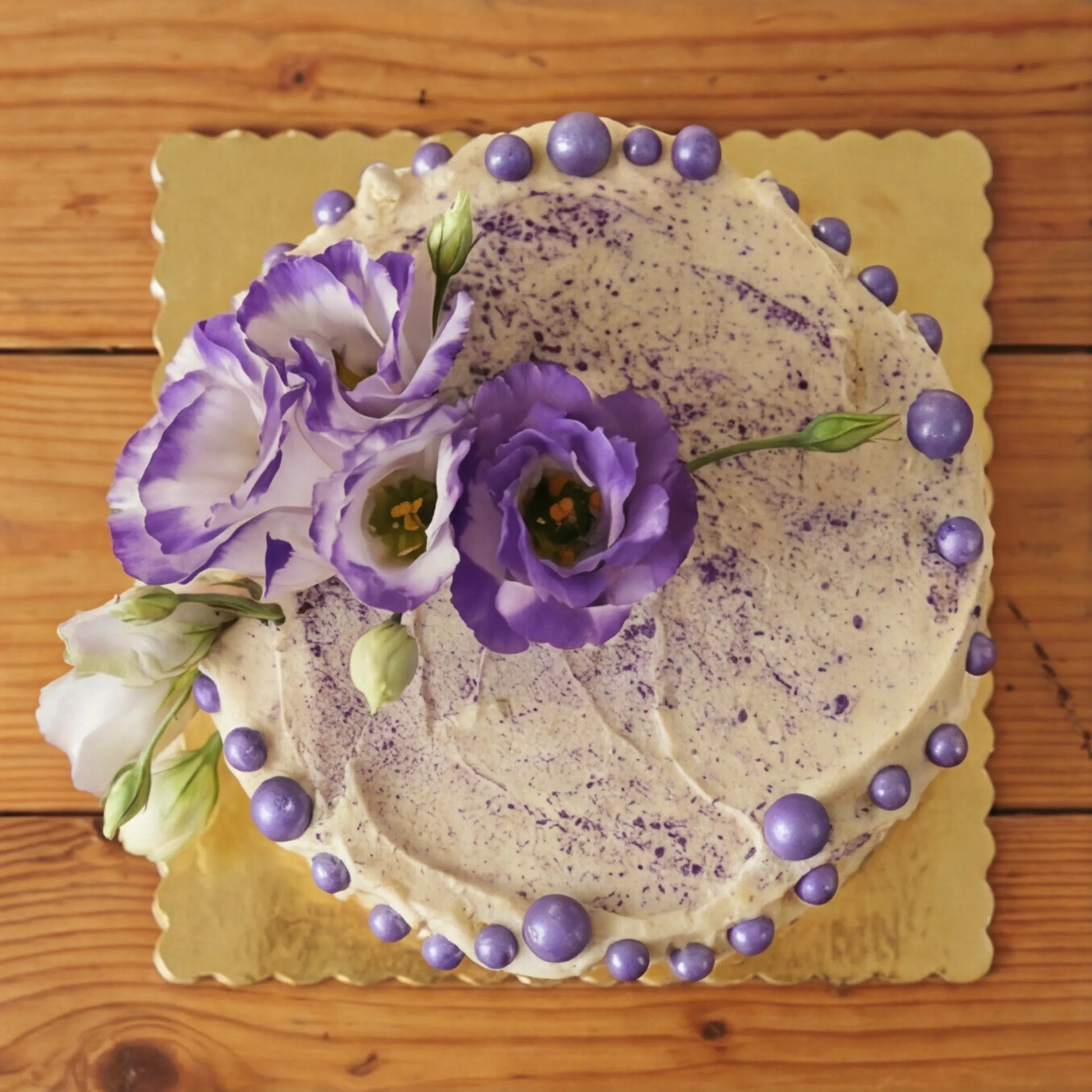 Overhead view of Creamy Violet Dream Cake showing purple speckled buttercream top and lisianthus crown