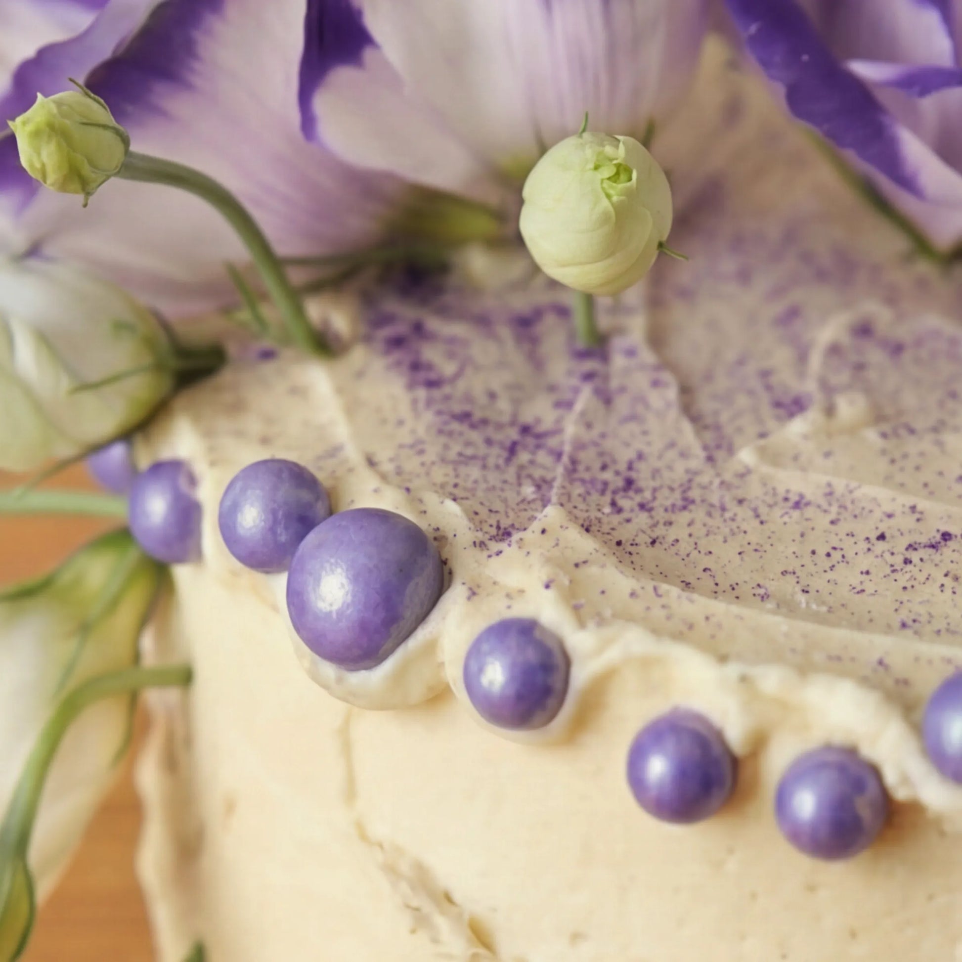 Macro of purple edible pearls and dusted buttercream finish on Creamy Violet Dream Cake by Flower Guy