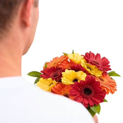 Daisy Delight Flower Bouquet close-up—bright gerbera daisies in red, orange and yellow tones, held in hand | Flower Guy