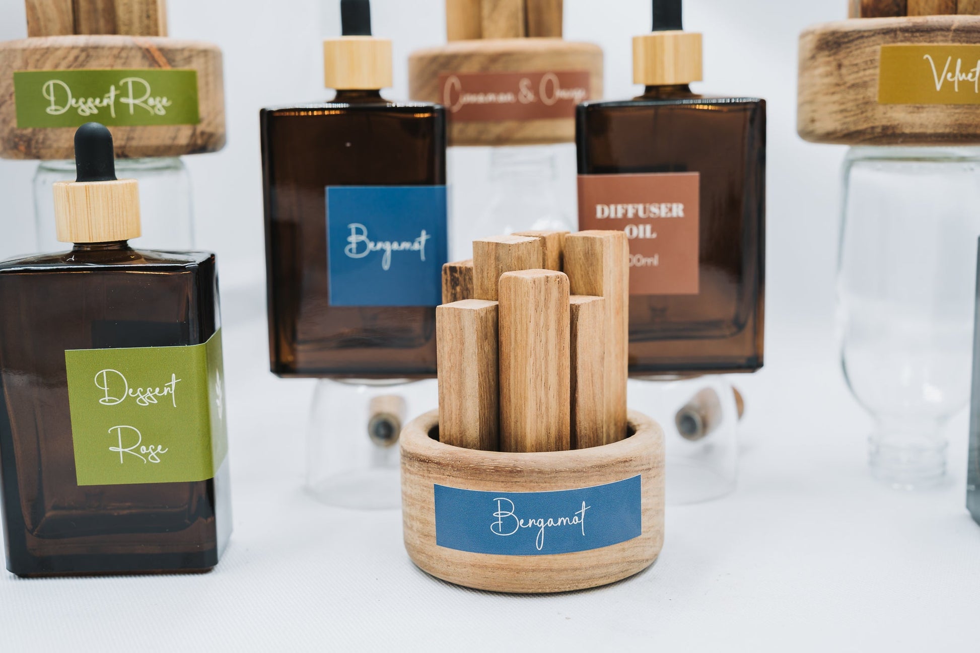 A display of diffuser oils with wooden diffusers on a white background