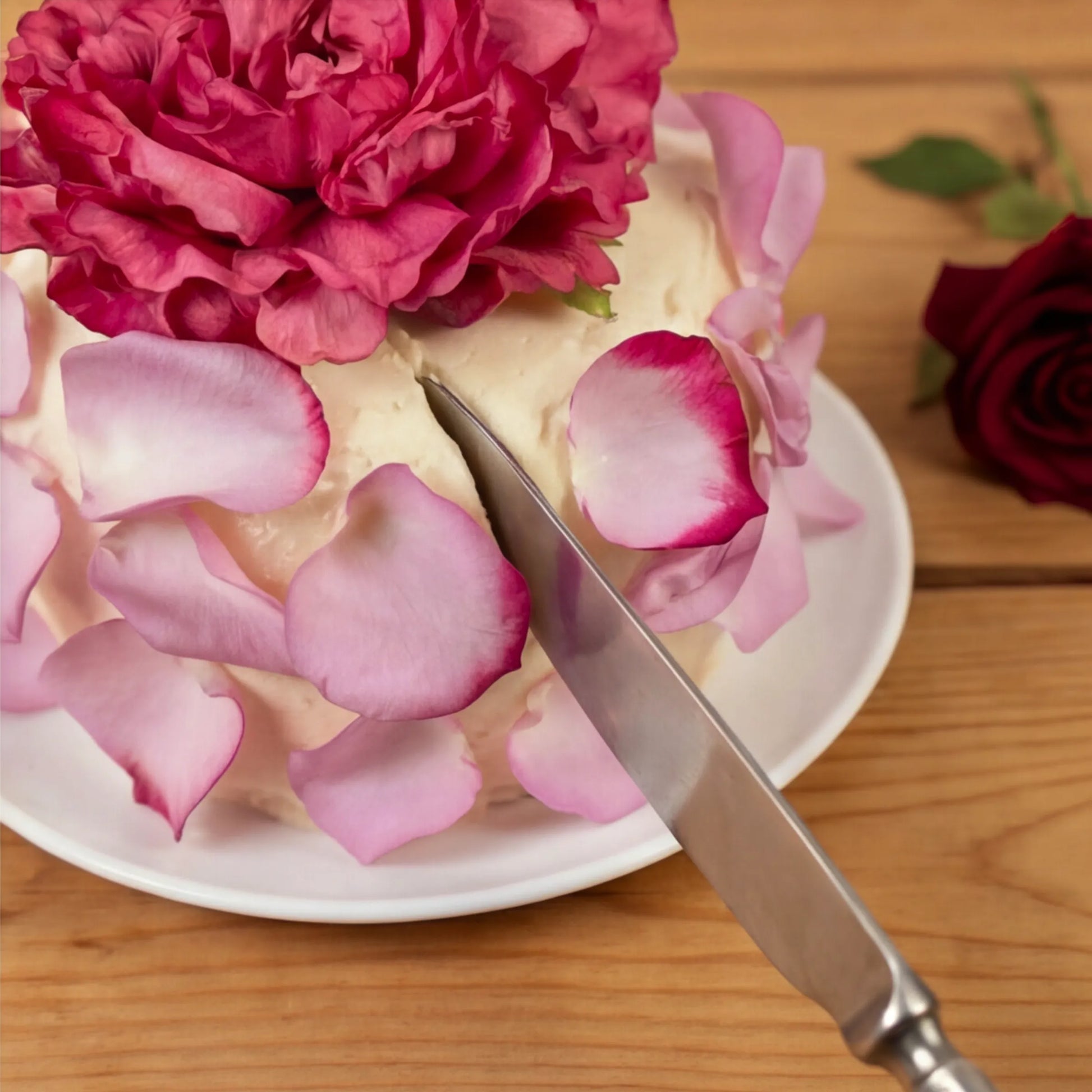 Cutting the Elegance Rouge Cake with knife, fuchsia peony and pink rose petals, by Flower Guy Cape Town