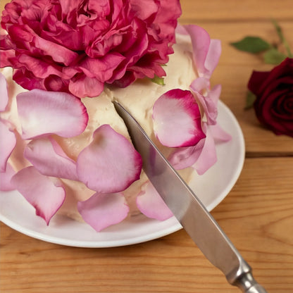 Cutting the Elegance Rouge Cake with knife, fuchsia peony and pink rose petals, by Flower Guy Cape Town