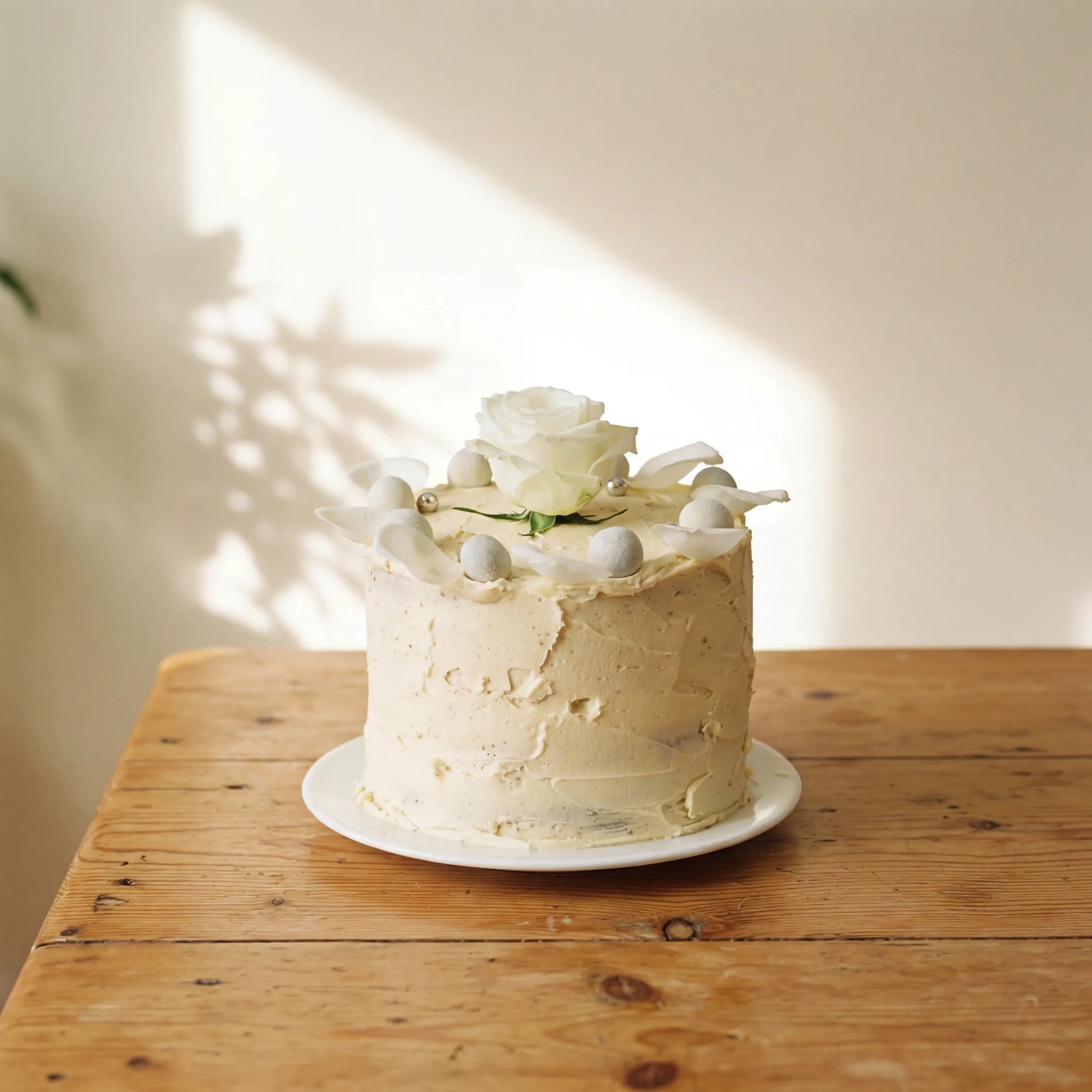 Elegant Rose Celebration Cake with white rose and silver pearls on white plate by Flower Guy Cape Town