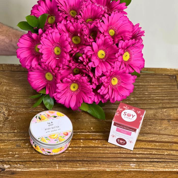 Bright Pink Gerbera Daisy bouquet being held by Flower Guy paired with Fig and Pear Body Butter and SOY Lites Mini Candle - Flower Guy