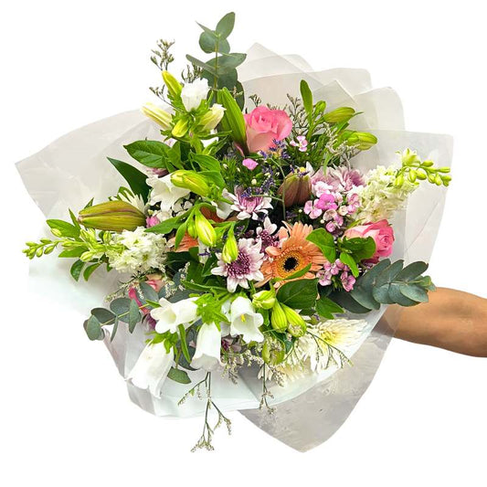 Free Spirit Bouquet—hand holding a whimsical mix with pink roses, lilies, sweet william and greenery, wrapped | Flower Guy