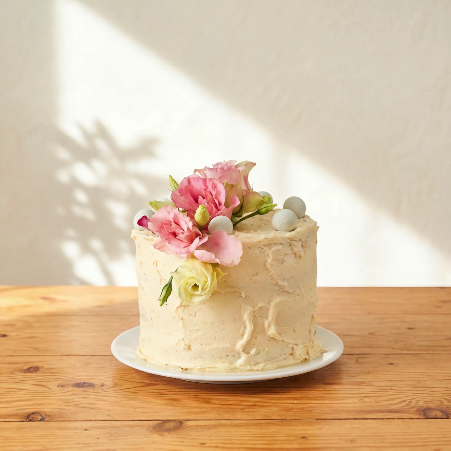 Garden Tea Party Cake with pink lisianthus, cream rose and pale chocolate pearls on rustic buttercream finish
