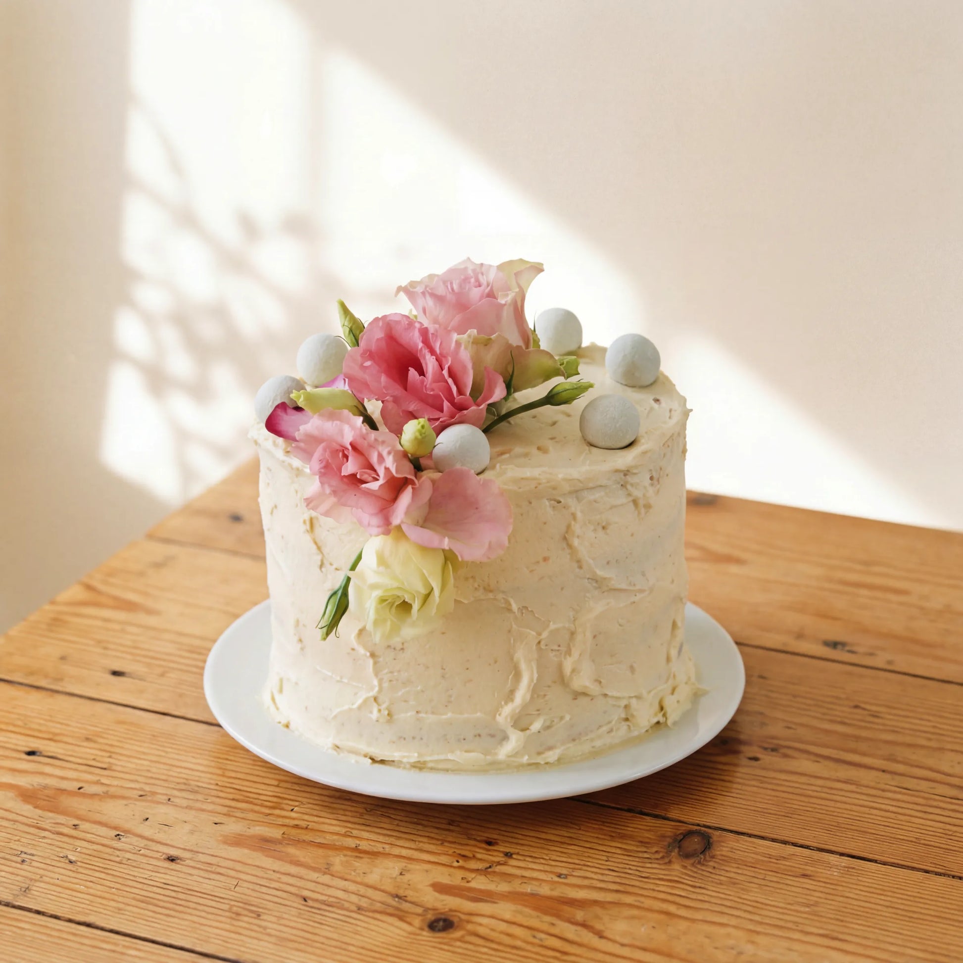 Garden Tea Party Cake side view showing rustic cream buttercream texture and fresh pink lisianthus crown