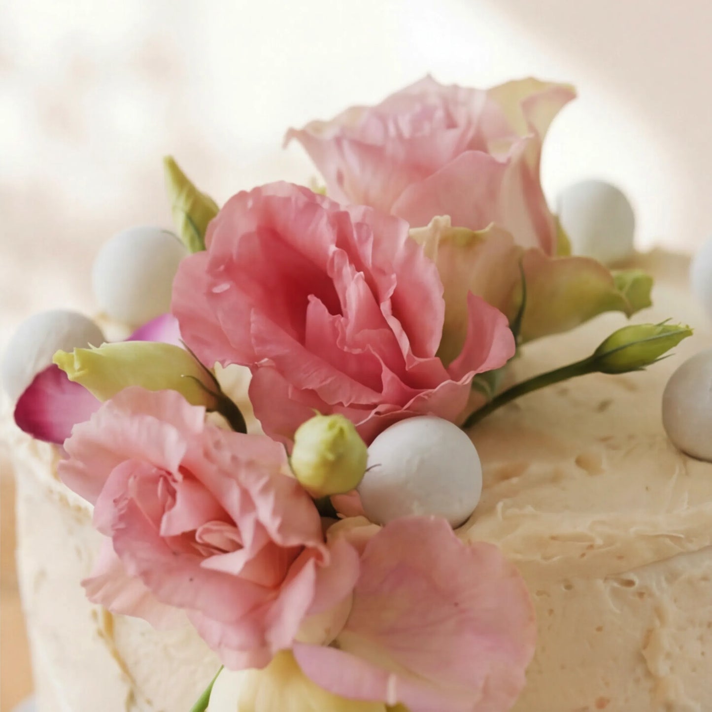 Close-up of Garden Tea Party Cake floral crown: pink lisianthus blooms, buds and white chocolate pearls