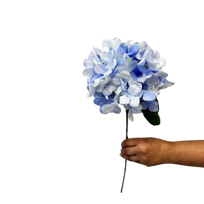 Hand holding a blue and white artificial flower against a white background