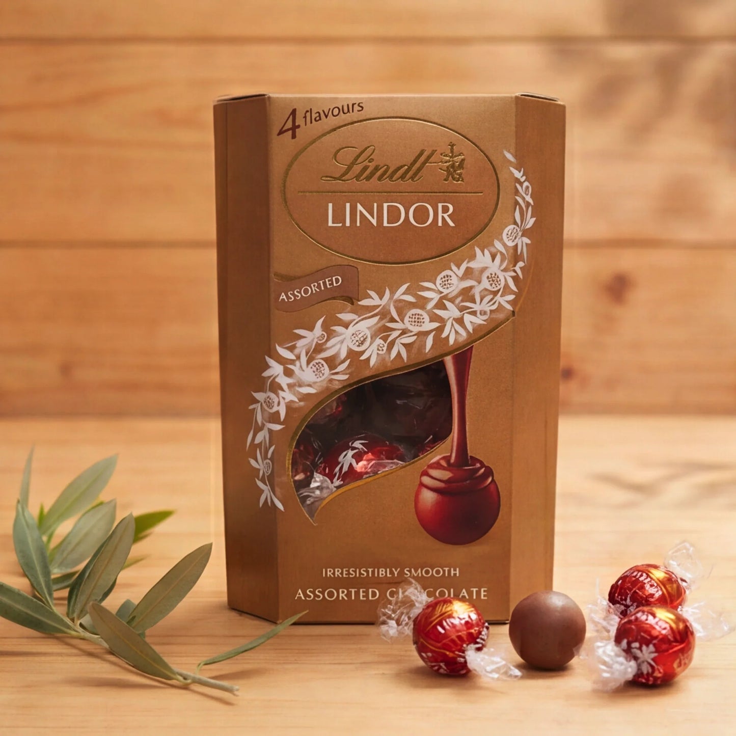 Lindt Lindor Assorted chocolate truffle box, 4 flavours, with red-wrapped Lindor truffles on a wooden table
