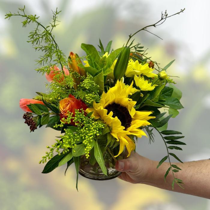 Make someone smile with whimsical Mr Brightside arrangement with orange and yellow blooms including cherry brandy roses and sunflowers - Flower Guy