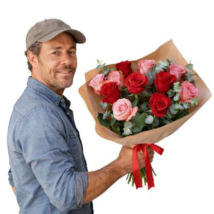 Nailed It bouquet—man holding red and blush rose bouquet with greenery, wrapped in kraft paper and red ribbon | Flower Guy