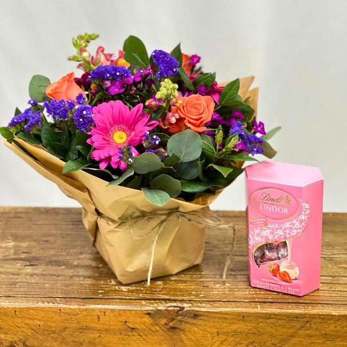 Mixed bouquet of orange roses, pink gerberas and purple statice with Lindt Lindor Strawberries and Cream White Chocolate - Flower Guy
