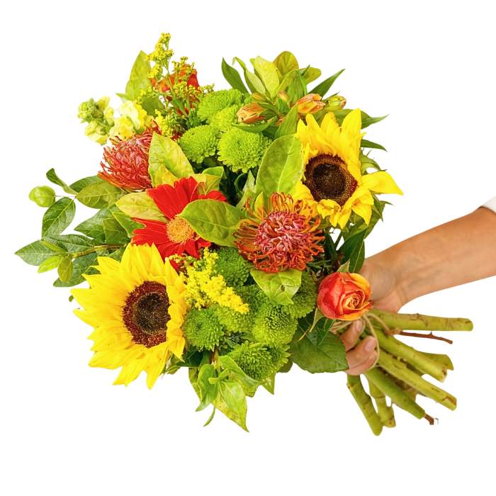 Ray of Sunshine Bouquet—hand holding bright mixed bouquet with sunflowers, orange roses, red gerberas and greenery | Flower Guy