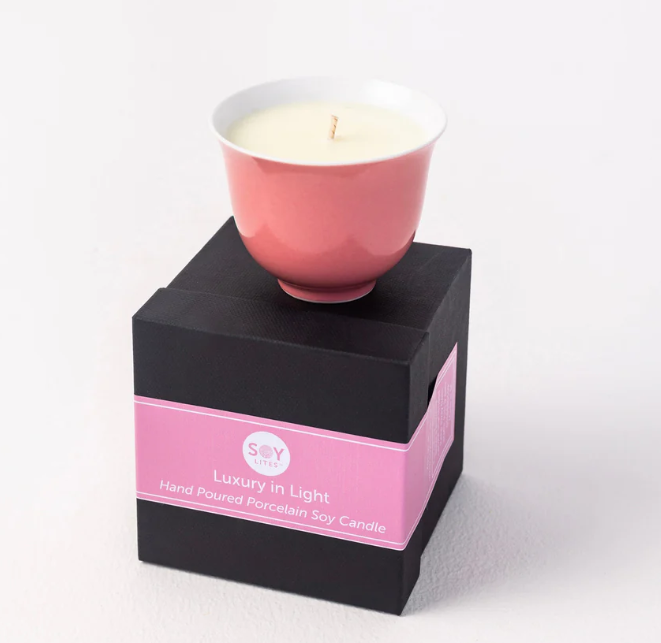 Pink candle in a black box with a pink label on a white background