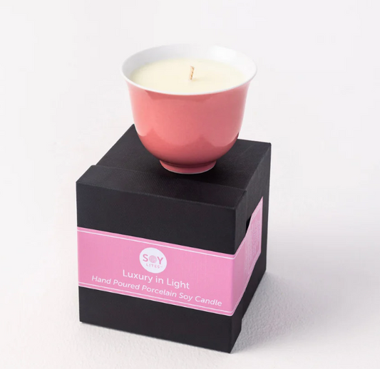 Pink candle in a black box with a pink label on a white background