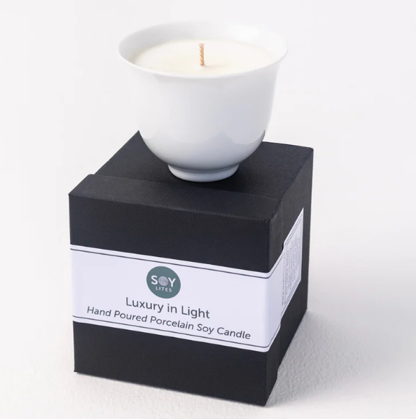 White ceramic candle in a black box with a label on a white background