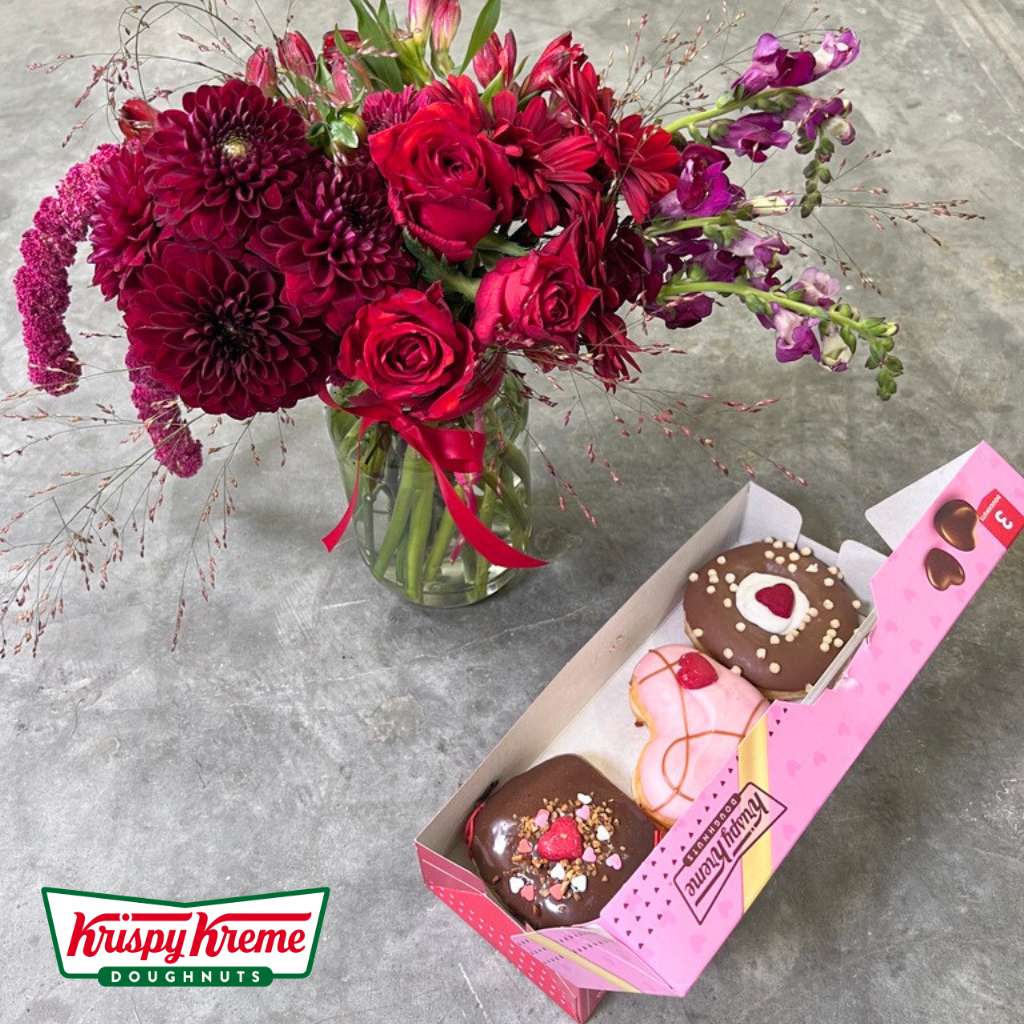 Glass jar full of red and pink flowers with Krispy Kreme doughnuts - Flower Guy