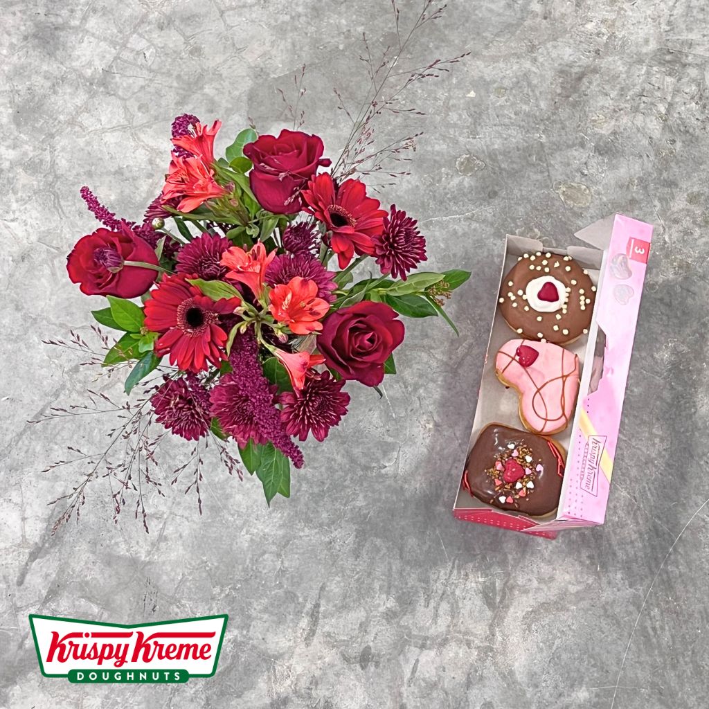 Elegant vase of red roses and gerberas with gourmet doughnuts by Flower Guy.
