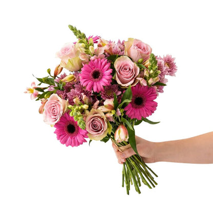 The Soft Touch pink flower bouquet from Flower Guy with soft pink roses, bright pink gerberas, pink alstroemeria and mauve chrysanthemums, hand-tied with natural raffia.