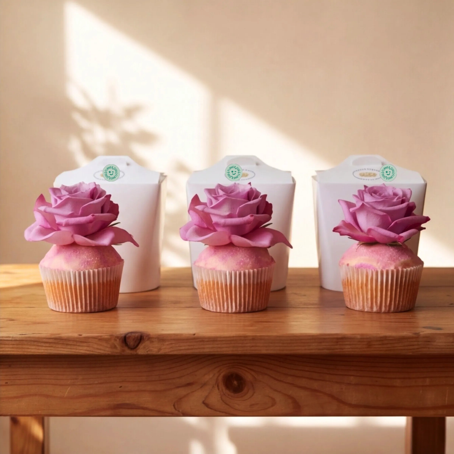 Three Flower Guy vanilla cupcakes displayed in a row with their individual white gift boxes behind them, Cape Town same-day cupcake add-on