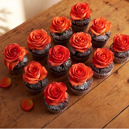 A dozen chocolate cupcakes arranged on a rustic wooden table, each topped with a vibrant orange rose and finished with icing-sugar dusting, Flower Guy Cape Town corporate and event add-on