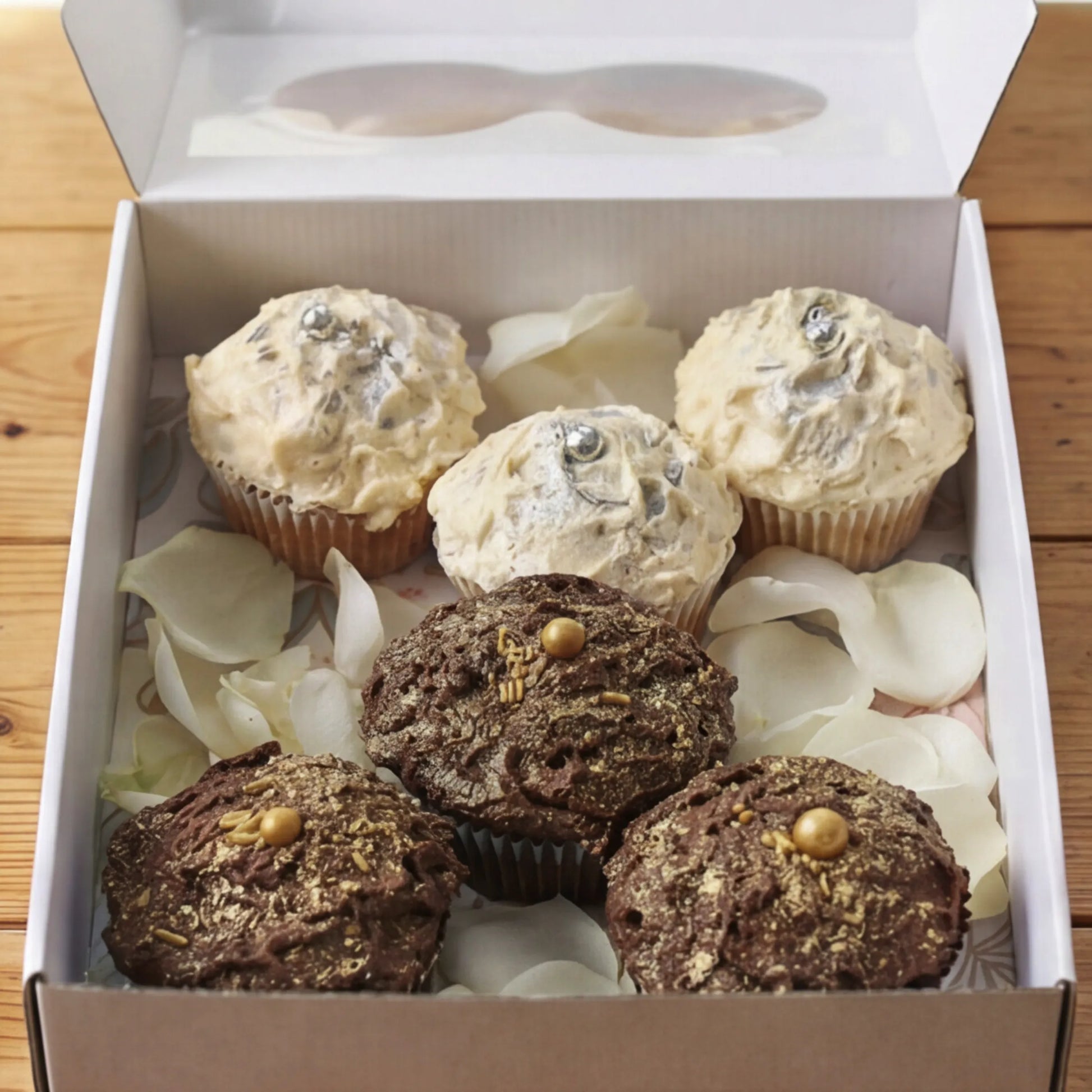Where Frosting Meets Fate cupcake box with 3 vanilla silver and 3 chocolate gold cupcakes on white rose petals