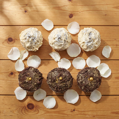 Overhead flat lay of Where Frosting Meets Fate vanilla and chocolate cupcakes with scattered white rose petals